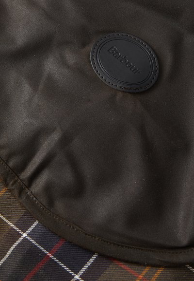 Тъмен плат с гладка текстура, овален черен логото на Barbour, и част от кафяво, червено и бяло каре.