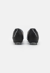 Melnas futbola kurpes ar baltām un zeltītām akcentiem, ar elegantu dizainu, noapaļotu pirkstu daļu un puscaurspīdīgiem radziņiem, lai nodrošinātu saķeri.