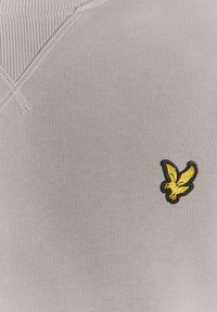 Szürke pamut pulóver bordázott nyakkivágással, bal mellrészen fekete szegélyű sárga hímzett sas logóval.