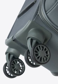 Šedá zavazadla se třemi otočnými kolečky. Kolečka mají design radiálního paprsku a jsou připevněna k pevné základně. Texturovaný látkový exteriér.