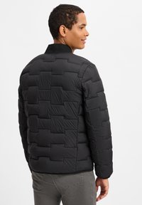 Black padded jacket with a textured pattern, featuring a stand collar and a lightweight design, seen from the side and back.