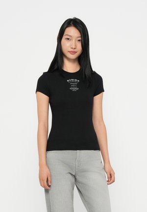 Black ribbed short-sleeve t-shirt with a round neckline, featuring a printed logo in white on the chest. Paired with light gray pants.