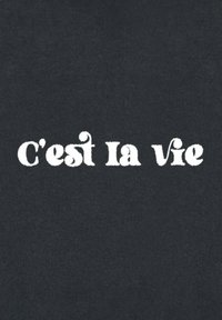Črn material z besedilom "C'est la vie" v velikih, teksturiranih belih črkah, v rahlo retro slogu pisave.