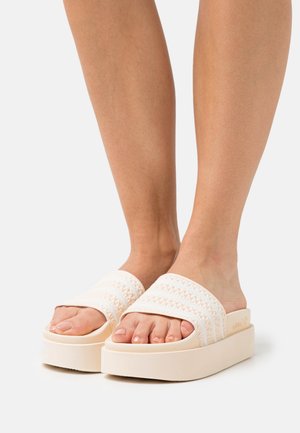 Sandales à plateforme en blanc cassé, présentant un design de bride tissée, un semelle ergonomique et une semelle épaisse et surélevée pour le confort.