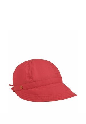 Red baseball-style cap with a small round metal emblem on the side and a tied fabric detail at the back.