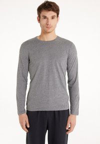 Šedé dlouhý rukáv tričko z měkké bavlněné směsi, s kulatým výstřihem a slim fit. Tkanina má lehkou texturu.