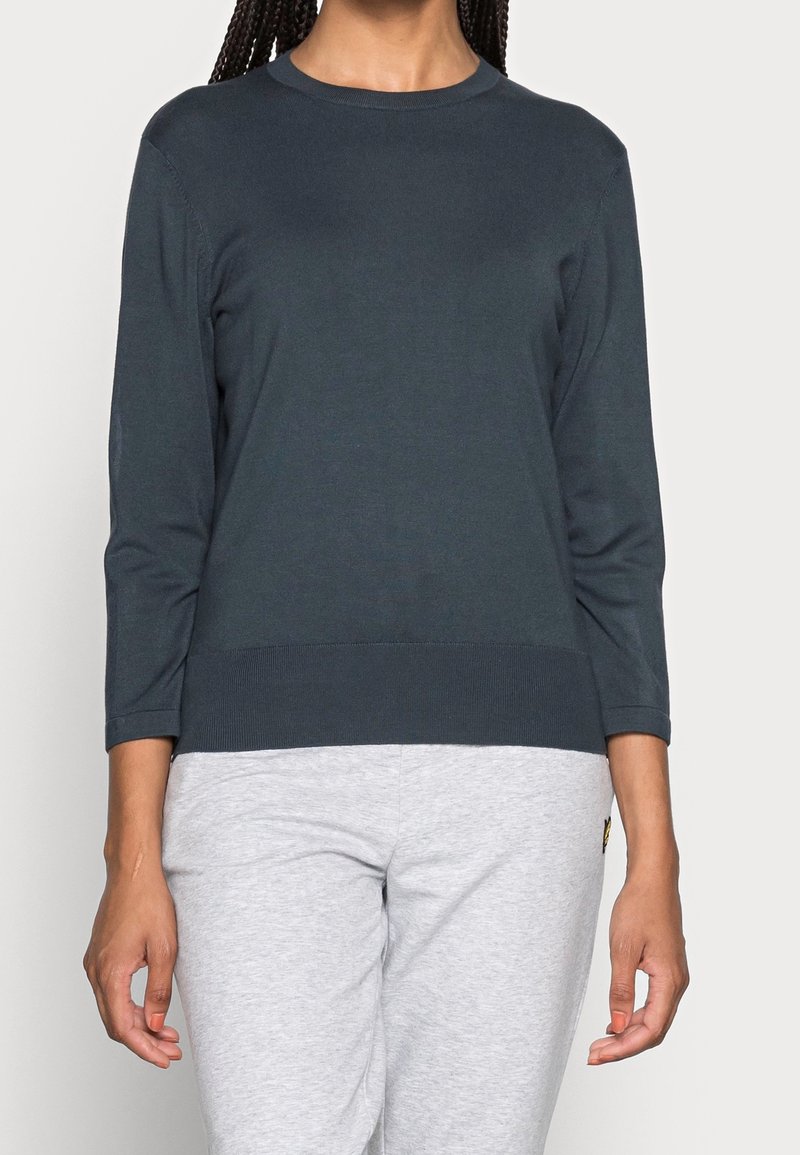 Dark gray long-sleeve sweater with a round neckline and ribbed hem. Soft fabric, fitted shape, and three-quarter length sleeves.
