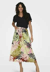 Falda maxi floral en verde, rosa y negro con patrones de hojas y detalles de botones. Combinada con una blusa negra de manga corta.