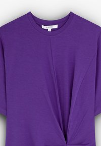 Paarse t-shirt met korte mouwen van zachte stof, met een voorste twistdetail en een ronde halslijn. Etiket zichtbaar aan de binnenkant met maat S.