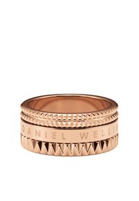Rose gold ring featuring three stacked bands, with geometric textures and engraved "DANIEL WELLING" on the middle band.