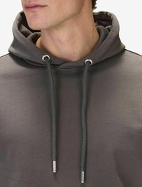 Grå hoodie med dragsko med silverfärgade metallspetsar, tillverkad av mjukt tyg med en slät textur och en strömlinjeformad design.