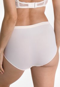 Hochgeschnittene weiße Baumwollunterhosen mit glatter Textur und elastischem Bund, ausgestattet mit nahtlosen Kanten und minimalen Nähtendetails.