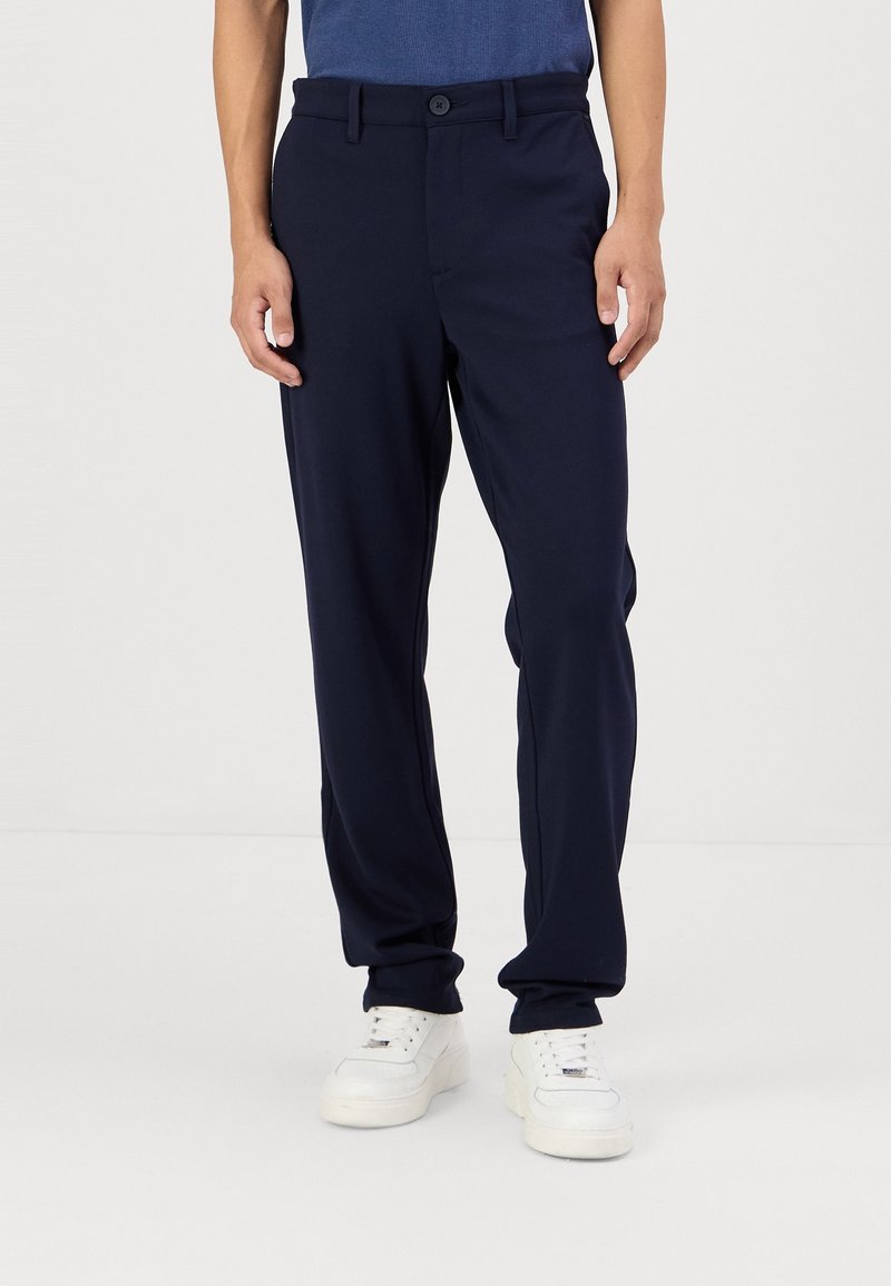 Pantalon bleu marine à coupe droite, avec fermeture par bouton et passants pour ceinture. Confectionné dans un tissu lisse, conçu pour une coupe décontractée.