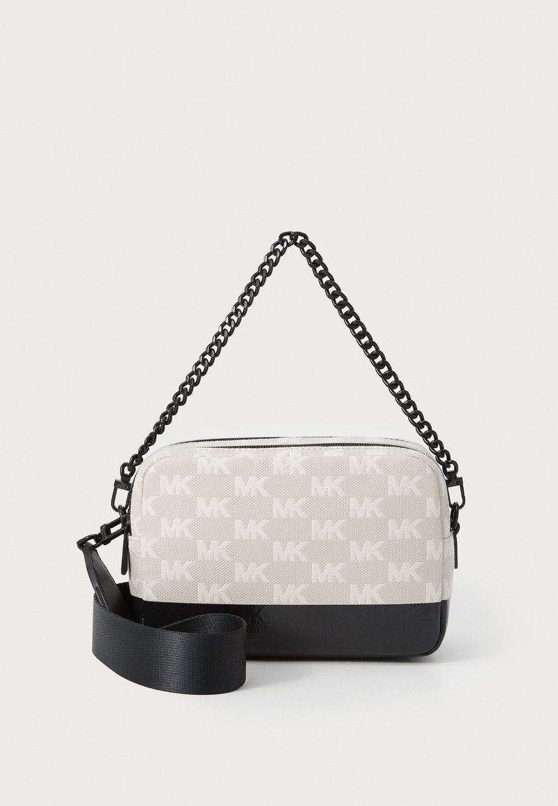 Kryžminė maišelis su raštuotu šviesiai pilku drobiniu paviršiumi, ant kurio yra MK logotipai, juodu sintetinio odos pagrindu ir grandininiu dirželiu su audinio akcentais.