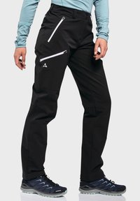 Schwarze Outdoor-Hose mit zwei weißen Reißverschlusstaschen und kleinem Logo, taillierte Passform, aus feuchtigkeitsableitendem Material gefertigt, strukturierte Oberfläche.