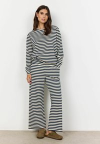Striped loungewear set with long sleeves and wide-leg pants in navy and cream. Includes pockets and paired with brown slip-on shoes.