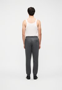 Γκρι φόρμα με μαλακό ύφασμα, διαθέτει ελαστική μέση, ριμπ μανσέτες και πίσω τσέπη, φορεμένη με λευκή αμάνικη μπλούζα.