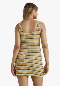 Strickkleid mit enganliegender Silhouette in mehrfarbigen Streifen von Grün, Gelb, Braun und Weiß, mit einem ausgeschnittenen Rücken.