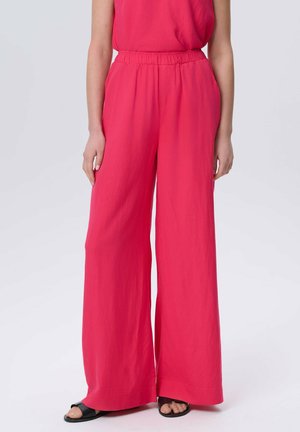 Wijde broek in levendig roze, gemaakt van lichte stof. Voorzien van een elastische tailleband en een gladde textuur, gestyled met open teen schoeisel.