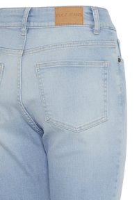 Achteraanzicht van lichtblauwe spijkerbroek met een leren merklabel met de tekst "PULZ JEANS" en grote achterzakken.