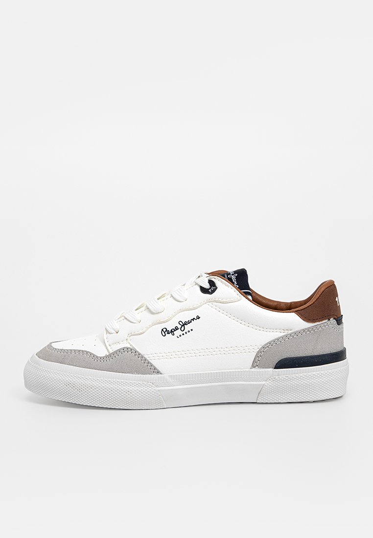 Zapatilla de cuero blanca con acentos de ante gris y un talón de cuero marrón. Cuenta con una suela de goma texturizada y una marca negra en el lateral.