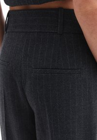 Pantaloni grigio scuro su misura con un motivo a righe, tessuto textured e una vita piatta con un discreto dettaglio della tasca posteriore.
