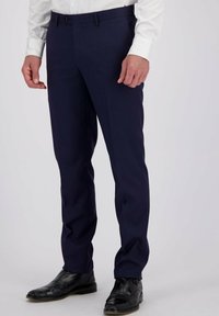 Marineblauwe op maat gemaakte broek met een soepele textuur, rechte voorkant en zijzakken. Geland met zwarte geklede schoenen en een wit overhemden.