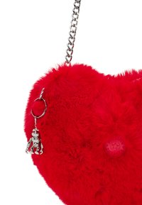 Borsa a forma di cuore rossa, realizzata in materiale soffice, con tracolla in catena argentata e un ciondolo a forma di robot in metallo attaccato a un portachiavi.