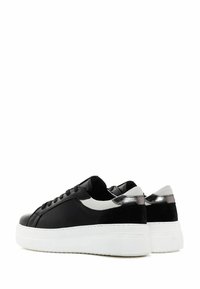 Zapatillas negras con un acabado de cuero suave, suela de plataforma blanca, acentos plateados en los talones y paneles laterales blancos contrastantes.
