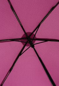 Ombrello rosa visto dal basso, con un tessuto a trama per il canopy, raggi in metallo nero e un mozzo circolare al centro.