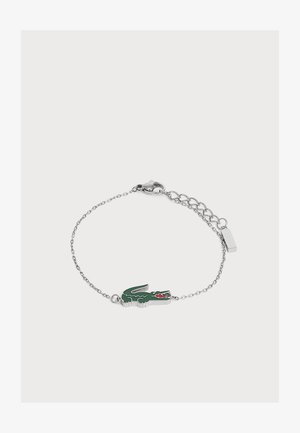 Bracelet chaîne en argent avec un pendentif crocodile vert et rouge et une fermeture réglable sur un fond clair uni.