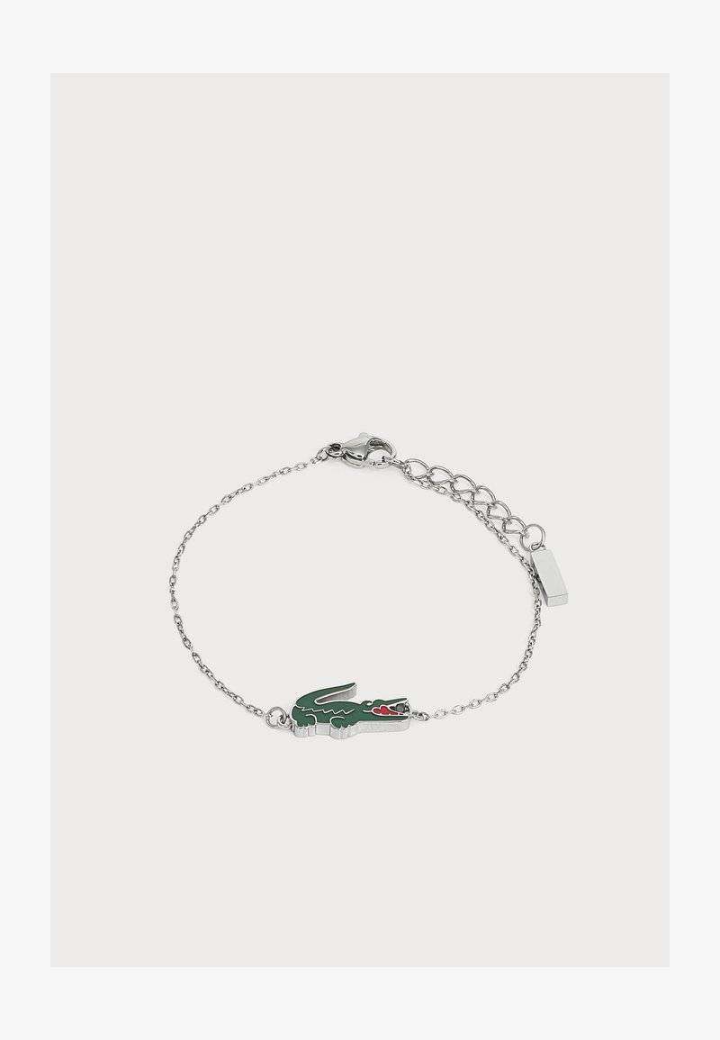 Bracelet chaîne en argent avec un pendentif crocodile vert et rouge et une fermeture réglable sur un fond clair uni.
