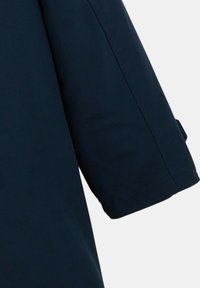 Vêtement bleu marine à manches courtes avec une texture lisse. Il présente un design structuré et des coutures apparentes le long du bord de la manche.