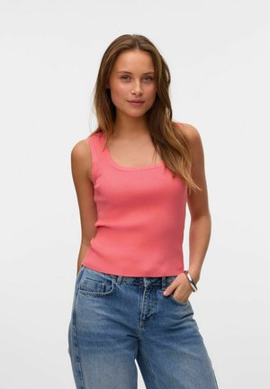 Koraalrood geribbeld tanktop met een vierkante halslijn. Gecombineerd met lichtblauwe denimjeans met een relaxte pasvorm en zichtbare zakdetails.