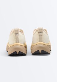 Baskets tricotées beige clair avec semelles épaisses couleur tan, languettes arrière et texte « FREEFORM » sur le talon, vues de dos sur fond blanc.
