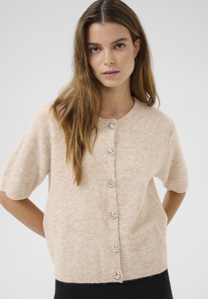 Cardigan beige a maniche corte realizzato in morbidissimo filato. Presenta un collo rotondo, bottoni in tonalità argento e orlo a coste.