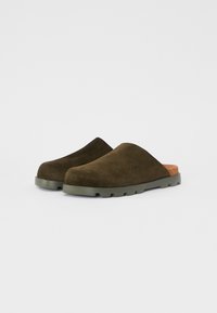 Zoccoli in suede verde oliva con finitura liscia, dotati di una morbida soletta beige e di una suola in gomma resistente e grip.