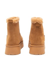 Stivaletti alla caviglia in camoscio color cuoio con un colletto soffice di pelliccia, dotati di una suola liscia e sottili dettagli testurizzati sul retro e sulla suola.