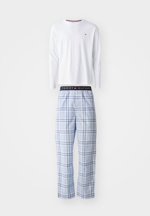 White long-sleeve shirt with round neckline above blue plaid pajama pants featuring a dark waistband with "TOMMY HILFIGER" logo.