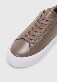 Καφέ δερμάτινα αθλητικά παπούτσια με στρογγυλή μύτη, επίπεδη λευκή σόλα και κορδόνια σε ίδιο χρώμα. Π�εριλαμβάνει διακριτική σήμανση στο πλάι. Λείο φινίρισμα.