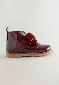 Burgunderfarbene Lackleder-Ankle Boots mit einem Samtblumenakzent, gestickten Details und einer Gummisohle. Seitenschlaufe für ein einfaches Anziehen.
