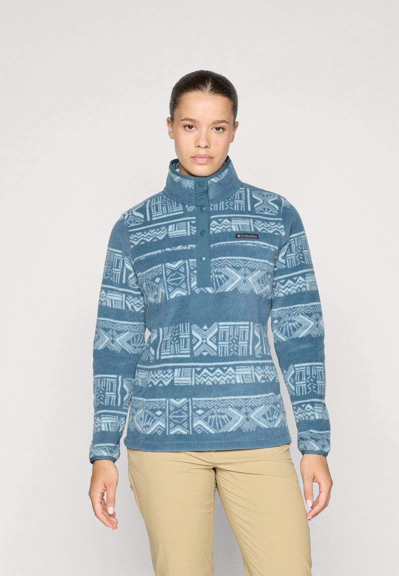 Fleece pullover i blå med geometriske mønstre, høj krave og trykknapper foran. Blød tekstur med en afslappet pasform.