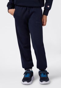 Marineblauwe sweatpants van zachte stof, met een elastische tailleband met trekkoord en geborduurd logo op het been. Afgemeten met zomen met boorden.