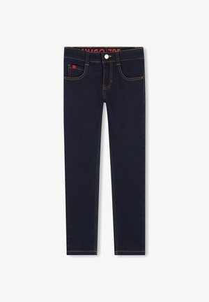 Mørkeblå jeans med slim fit, med gule sting, fem lommer og en liten rød logo foran. Glatt denimtekstur.