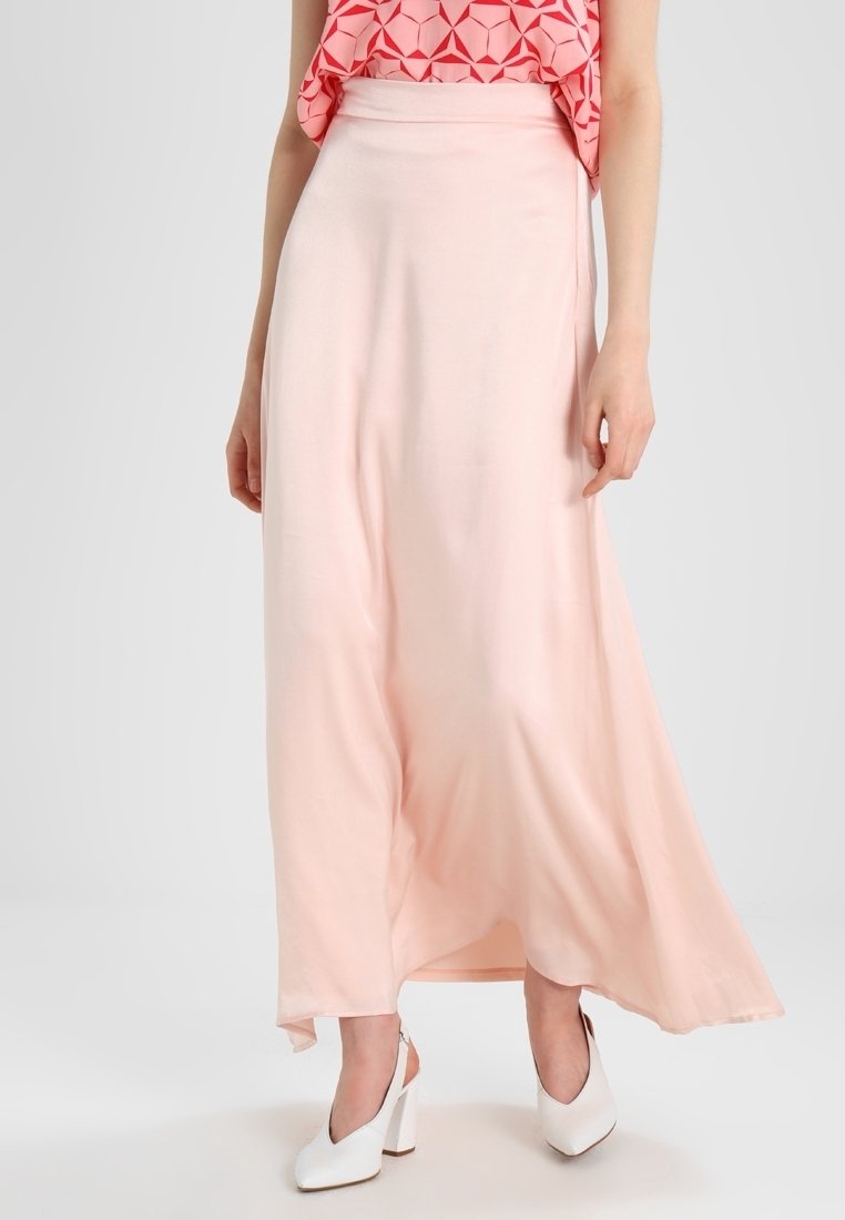 Lång, flödande rosa kjol i smidig tyg, med hög midja och en något utsvängd fåll. Bärs med vita klackskor.