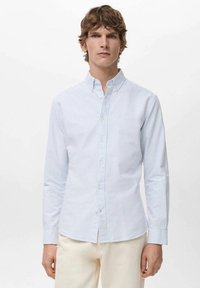 Camisa de botones con rayas en azul claro y blanco. Cuenta con cuello, mangas largas y una textura sutilmente brillante. Tejido suave, corte regular.