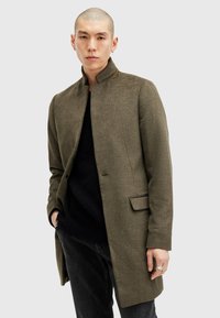 Cappotto in misto lana verde oliva con colletto alto, chiusura a singolo bottone e tasche laterali. Texture sottile con vestibilità su misura.