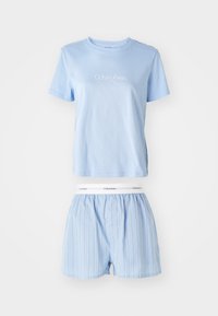 Světle modré bavlněné tričko s logem "Calvin Klein" nad odpovídajícími pruhovanými boxerkami se elastickým pasem. Jednoduchý, pohodlný set nočního prádla.