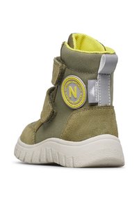 Bottines verte olive en daim et tissu avec des accents jaunes, des sangles Velcro et une semelle en caoutchouc blanc à motif texturé.