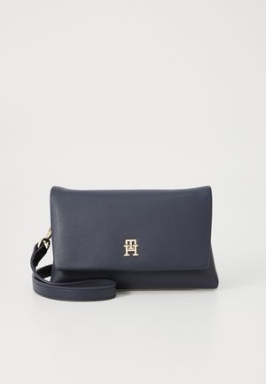 Pochette en cuir bleu marine au design structuré, avec un logo doré et une bandoulière amovible. Texture lisse et style minimaliste.